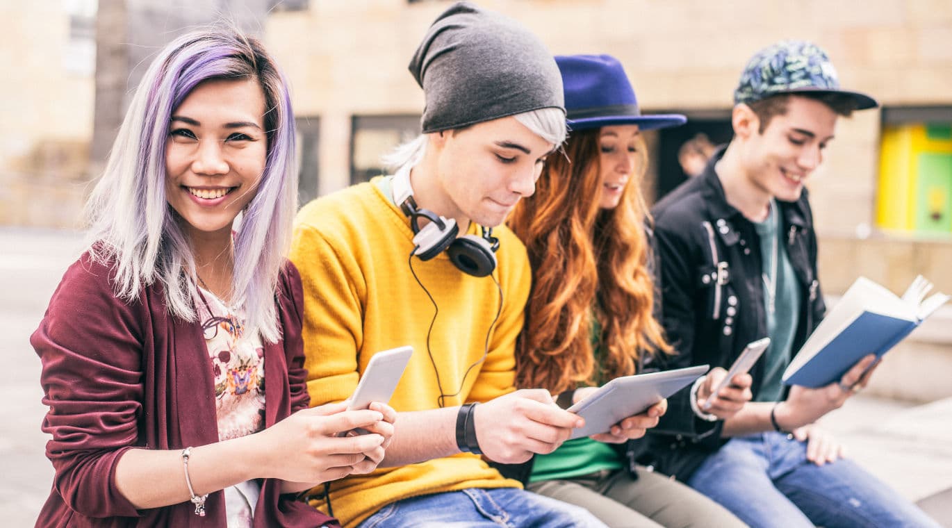 Junge Menschen schauen im Freien in Tablet und Handy