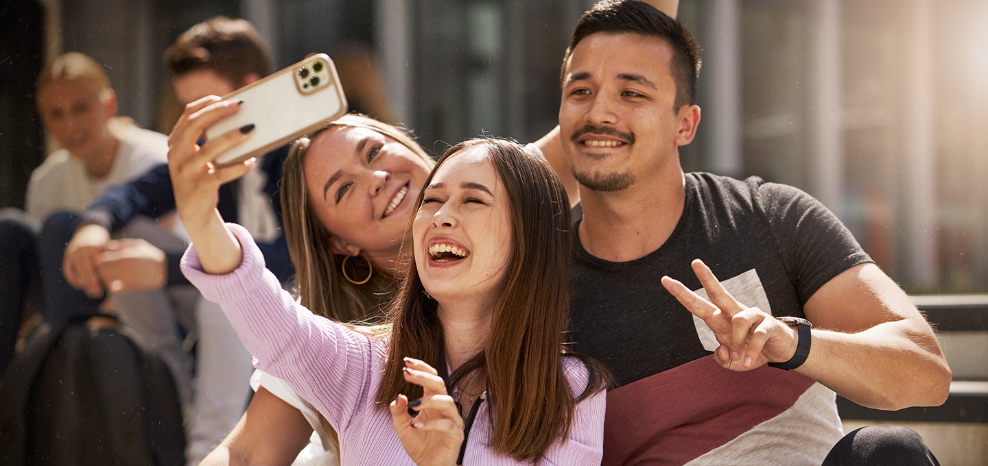 Eine Gruppe auf dem Campus macht Selfies mit der Handykamera